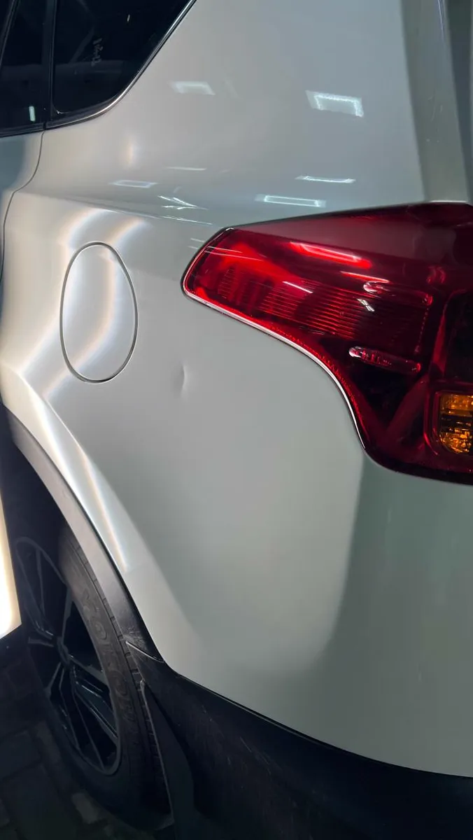 Вмятина на заднем крыле белого Toyota RAV4 у лючка бензобака — до ремонта